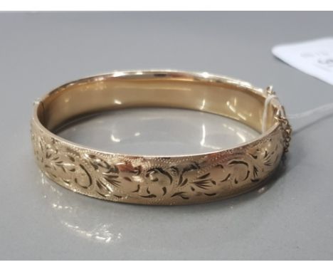 1/5 9CT GOLD BANGLE WITH METAL CORE FERN CUT ETCHED TO ONE SIDE AND HAVING A SAFETY CHAIN 21.7G GROSS