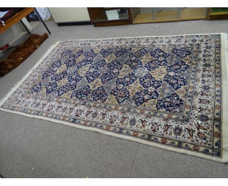 A PERSIAN STYLE 100% WOOL HAND KNOTTED CARPET, cream and blue ground with central repeating pattern and triple border, with t