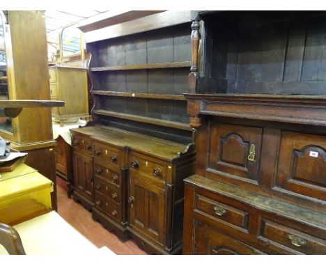 AN OAK WELSH DRESSER, mid to late 19th Century having a shaped three shelf rack over a breakfront base having four centre ope