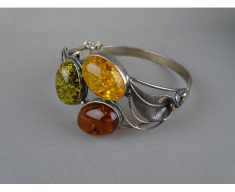 AN UNMARKED SILVER LEAF BRACELET having three large cabochon amber stones in green, light orange and dark orange respectively