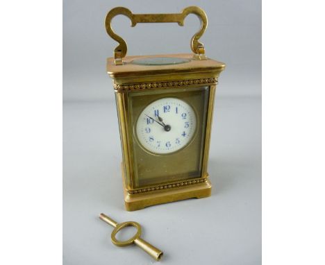 A FRENCH GILT BRASS CARRIAGE CLOCK, the enamel dial with blue Arabic numerals and satin gilt mask, 15 cms high handle up, wit