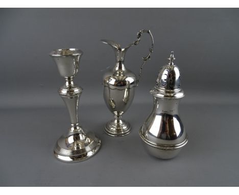 A SILVER SUGAR SIFTER, a single candlestick and a small ewer type jug both having loaded bases, Birmingham 1920, 1925 and 925