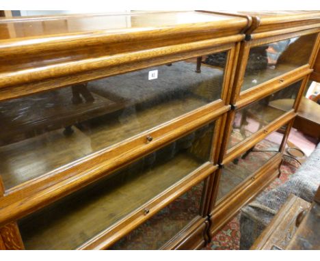 A PAIR OF GLOBE WERNICKE THREE SECTION LIGHT OAK STACKING BOOKCASES with labels, 115.5 cms high, 86.5 cms wide, 27 cms deep