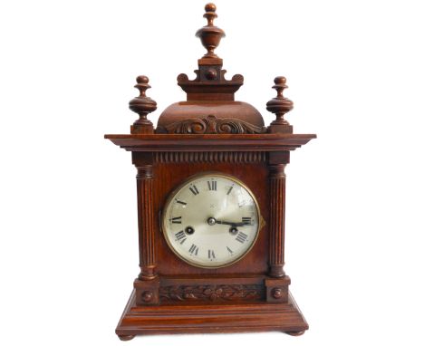 A late 19th century walnut eight-day mantle clock; the pediment finials above a silvered dial with Roman numerals, the gilded