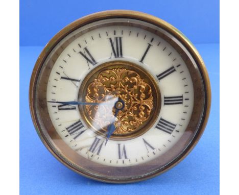 A 19th century bedside-style clock; brassed case, cream-enamel dial with Roman numerals and ornately pierced and gilded centr
