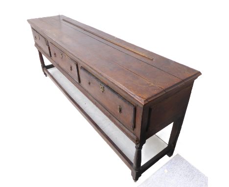 An 18th century oak dresser base; the large outset moulded top above three frieze drawers with mahogany crossbanding, the dra