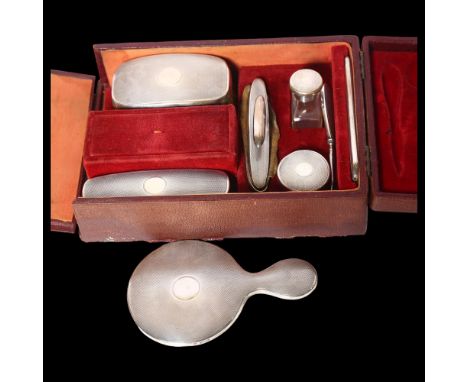 A George V engine turned silver-backed travelling leather vanity case, comprising a small hand mirror, brushes, rouge pot etc