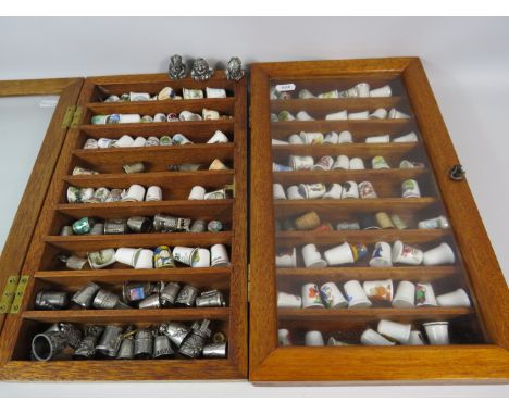 Large selection of various ceramic and pewter and ceramic thimbles in 2 glass display cases.