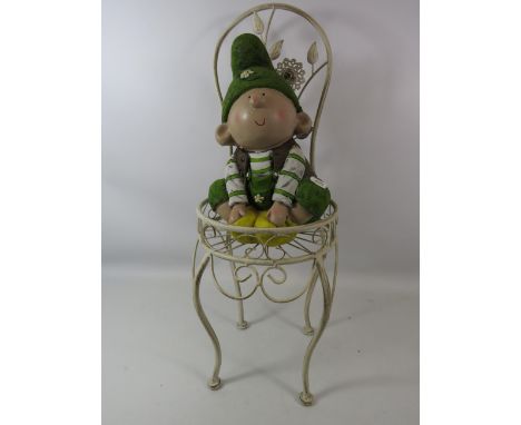 A Ceramic gnome sitting on a metal chair, the chair is approx 25" Tall.