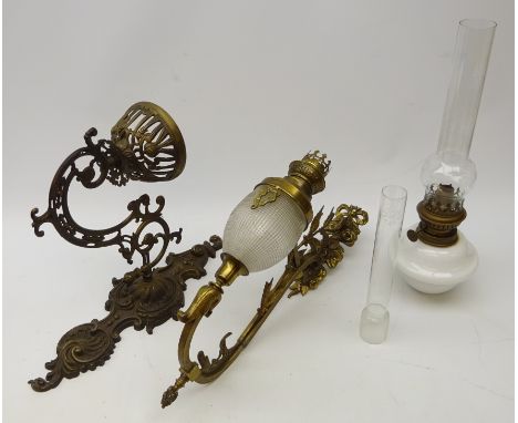 Cast brass wall mounting oil lamp, openwork cast bracket with milk glass oil lamp and chimney, H40cm and a similar continenta