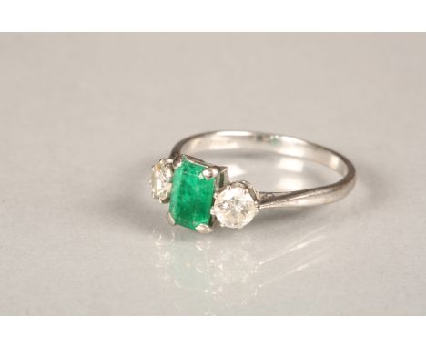 18 carat white gold diamond and emerald ring, the emerald flanked either side by a 0.25 carat brilliant cut diamond. Ring siz