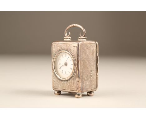 Silver cased travel clock, engine turned decoration raised on bun feet, French time piece, white enamel dial with black Roman