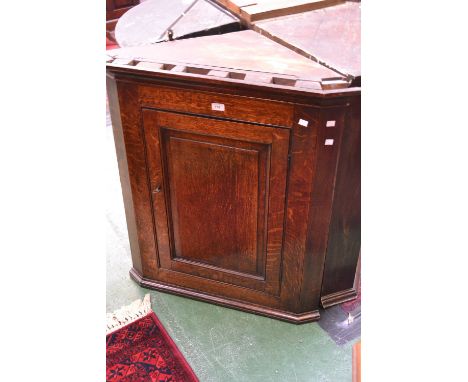 A George III oak splay front wall mounted corner cupboard, outswept cornice, fielded panel door enclosing shelving