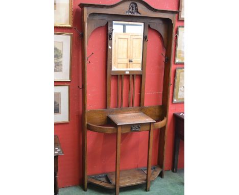 A 1930/40's oak hall stand, arched pediment over bevel edge mirror and hooks to top, single drawer flanked by stick stands to