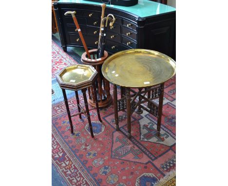 A circular Indian brass topped table; a brass topped table; a circular stick stand; two umbrellas and two walking sticks 