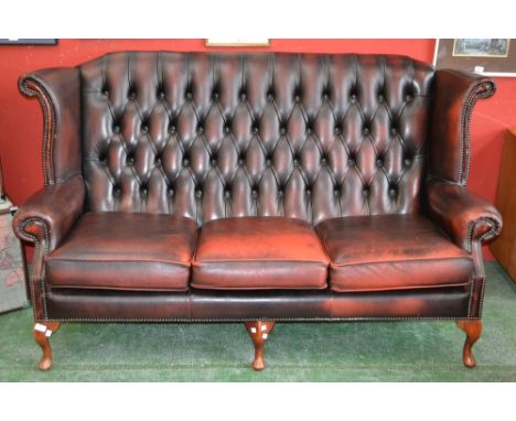 A modern button upholstered leather wingback three seat sofa.