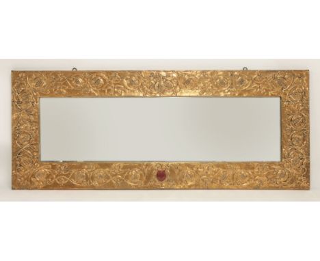 An Arts and Crafts copper embossed overmantel mirror, decorated with pomegranates and scrollwork, the centre inset with a rub