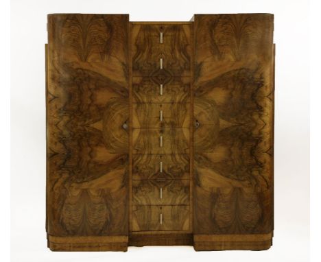 An Art Deco walnut compactum wardrobe,the inverted front centred with eight drawers with hexagonal painted pencil handles, fl