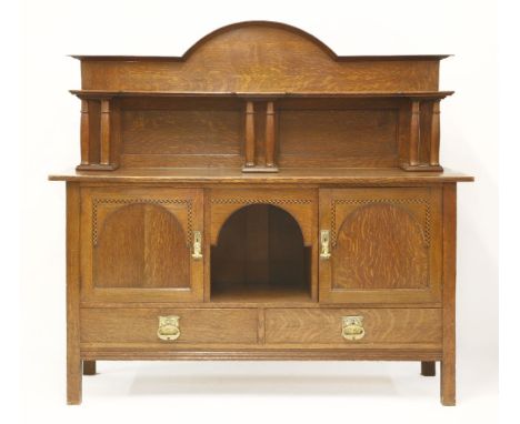 An Arts and Crafts oak sideboard,with an arched top with a shelf over columns above a well, flanked with herringbone inlaid c