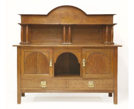 An Arts and Crafts oak sideboard,with an arched top with a shelf over columns above a well, flanked with herringbone inlaid c