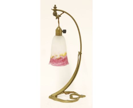 A brass table lamp,with a scrolling brass stand, fitted with a mottled white yellow and pink glass shade, marked 'Muller Frèr