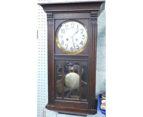 A mid 20thC oak cased wall clock, the 17cm diameter dial with Arabic numerals, flanked by acanthus capped columns and fronted