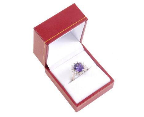 A dress ring, claw set with central purple stone, with floral surround of small diamonds on a part pierced shank, size M.