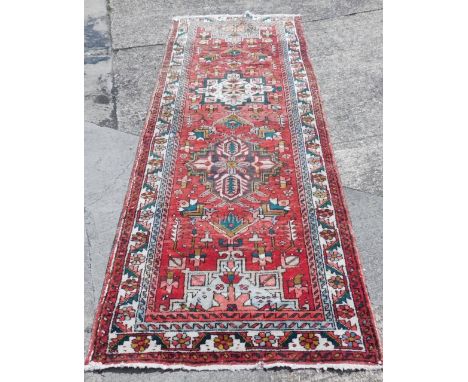 A vintage washed red ground Persian runner, in traditional medallion pattern, 310cm x 115cm. 