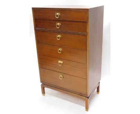 A G-Plan teak narrow chest, of six graduated drawers, each with brass ring handles on shaped stand with brass feet, stamped t