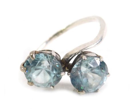 A crossover dress ring, claw set with two blue Zircon, unmarked, size M.