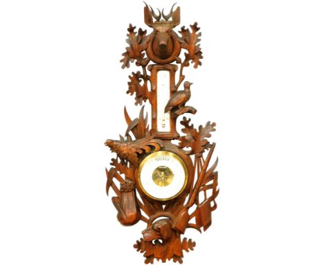 An early 20thC Black Forest barometer and thermometer, heavily carved with stag finial, with partridge leaves and ferns, with