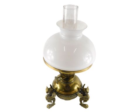 An early 20thC brass oil lamp, with clear glass chimney, milk glass shade and brass reservoir, stamped Use Only Paraffin, on 