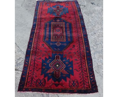 A heavy pile red and blue Persian Nahavan rug, in vintage medallion design, 215cm x 100cm.  
