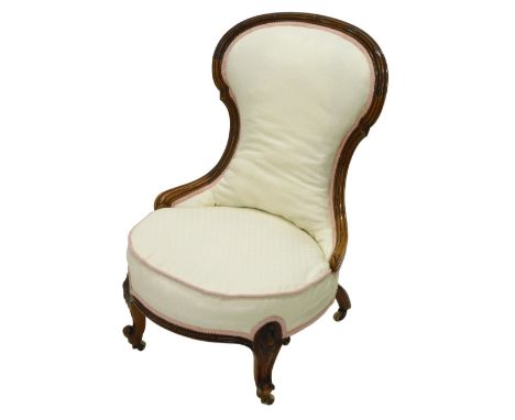 A Victorian walnut nursing chair, with a show frame, a padded back and seat, on cabriole legs with ceramic castors.