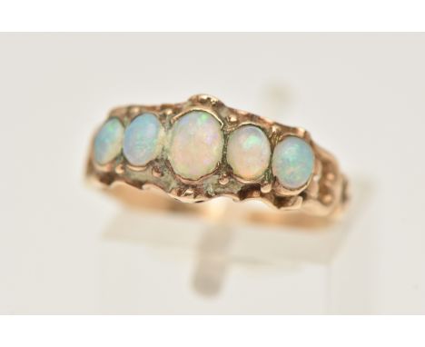 A YELLOW METAL OPAL RING, set with a row of five graduating oval opal cabochons, each collet set with a scrolling rim, open w