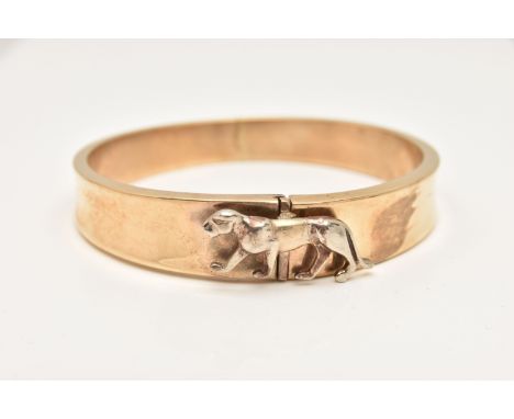 A YELLOW METAL HINGED BANGLE, the tapered hinged hollow bangle with a white metal wild cat push piece clasp, approximate widt