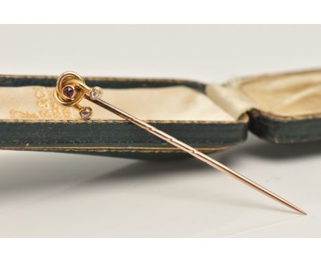 A CASED YELLOW METAL STICK PIN, set with two rose cut diamonds and a ruby, scroll mount, unmarked, approximate gross weight 1