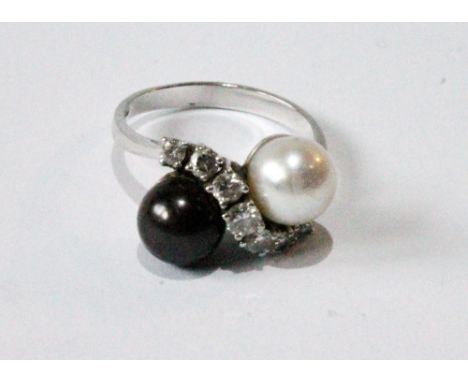 Ring with a white and black pearl, a wavy band of seven diamond brilliants between, in 18ct white gold, '.750'.