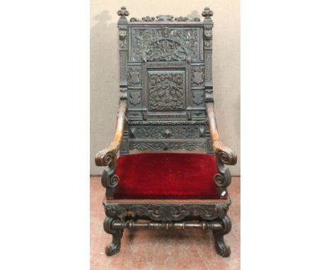 17th century carved oak armchair, the panelled back with masks, cherubs and foliage over acanthus arms, red upholstered seat 