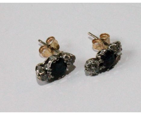 Near pair of earrings, each made from a diamond and sapphire three-stone ring.