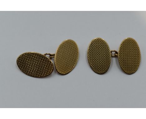 A pair of 9ct gold cufflinks of oval form having engine turned chequered decoration and chain connectors