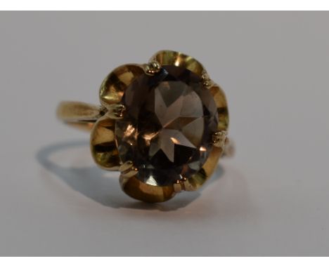 A lady's dress ring having an oval smoky quartz in an open frilled claw set mount on a 9ct gold loop, size P