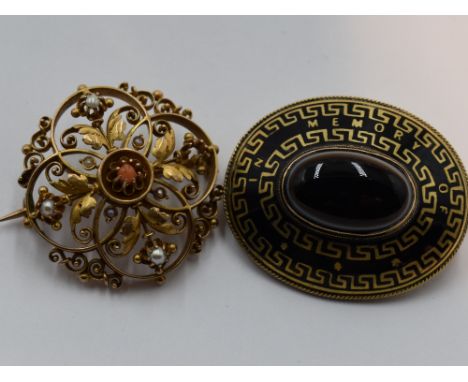 A yellow metal brooch having central coral pearl within an open foliate and scroll mount having seed pearl decoration, no mar