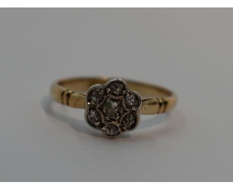 A lady's dress ring having an old cut diamond chip daisy cluster in a pave mount to shaped shoulders on a yellow metal loop s