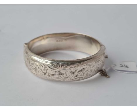 A hollow hinged silver bangle with scroll decoration 27g