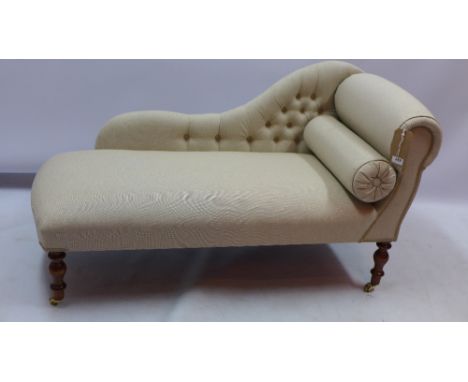 A contemporary ivory upholstered chaise longue with button back and mahogany legs raised on castors L 130cm  