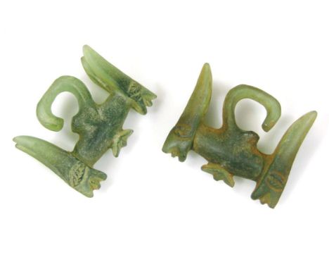 A pair of large green jade earrings, of shaped outline, set with figureheads, with original traces of red decoration, probabl