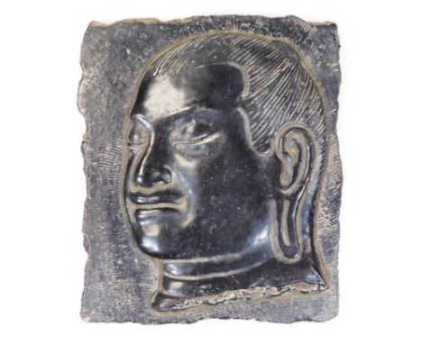 A ceramic tile, in black slate finish with raised Buddha head, side profile, unmarked, 17cm x 14cm.