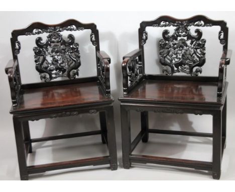A pair of Chinese Qing period hardwood throne chairs, with serpentine backs, heavily carved scroll and floral splats, shaped 