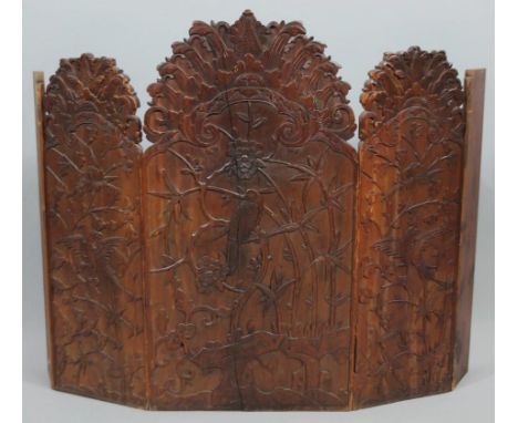 A Meiji period Japanese hardwood firescreen, with shaped top and rectangular outline with a concertina action, heavily raised